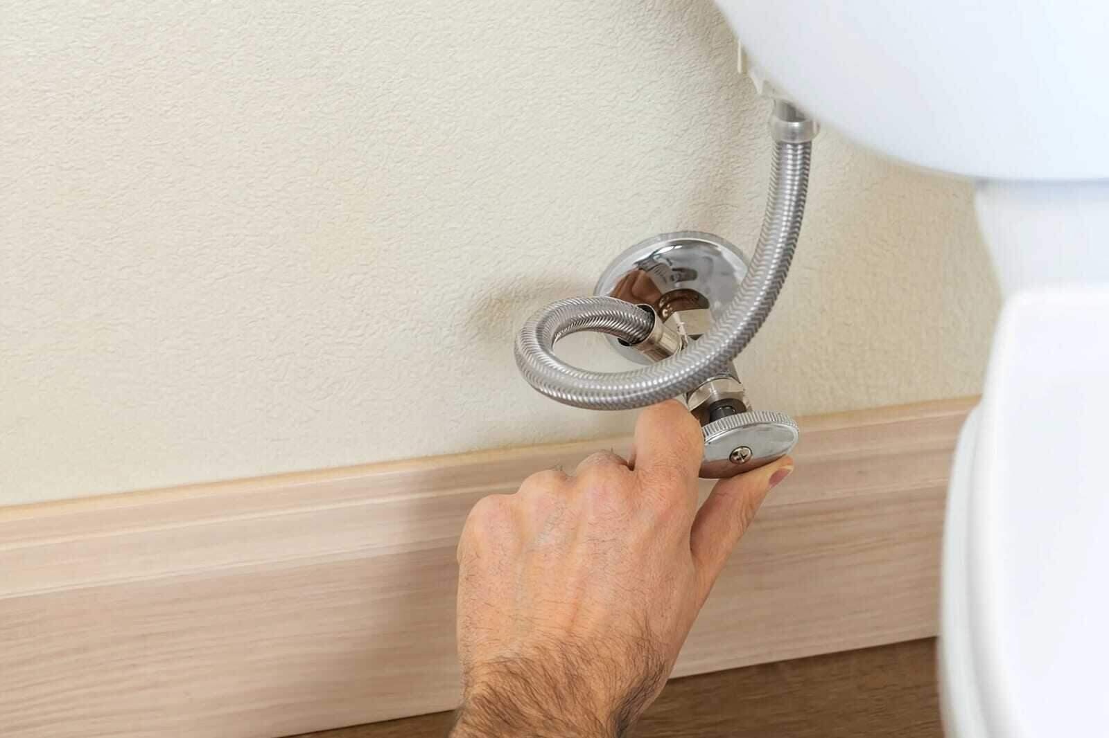 Hand shutting off the main water supply valve after a leak