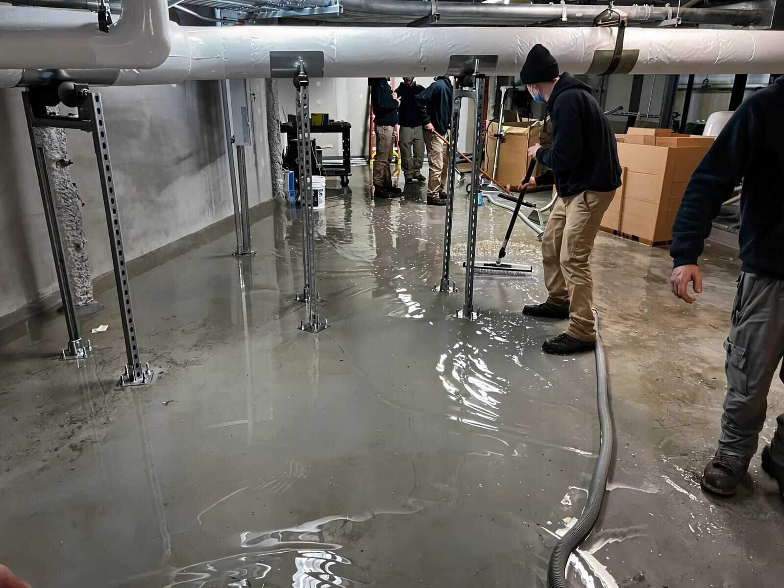 Restoration crew extracting standing water from a flooded room