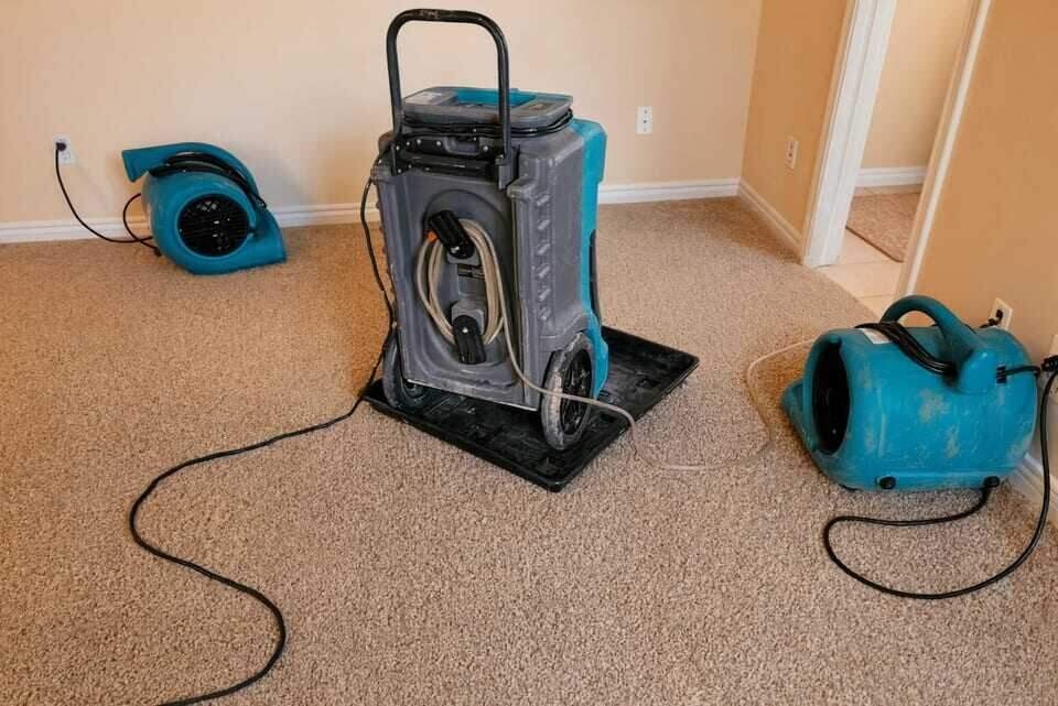 Air movers and a dehumidifier running during structural drying in a Dallas home