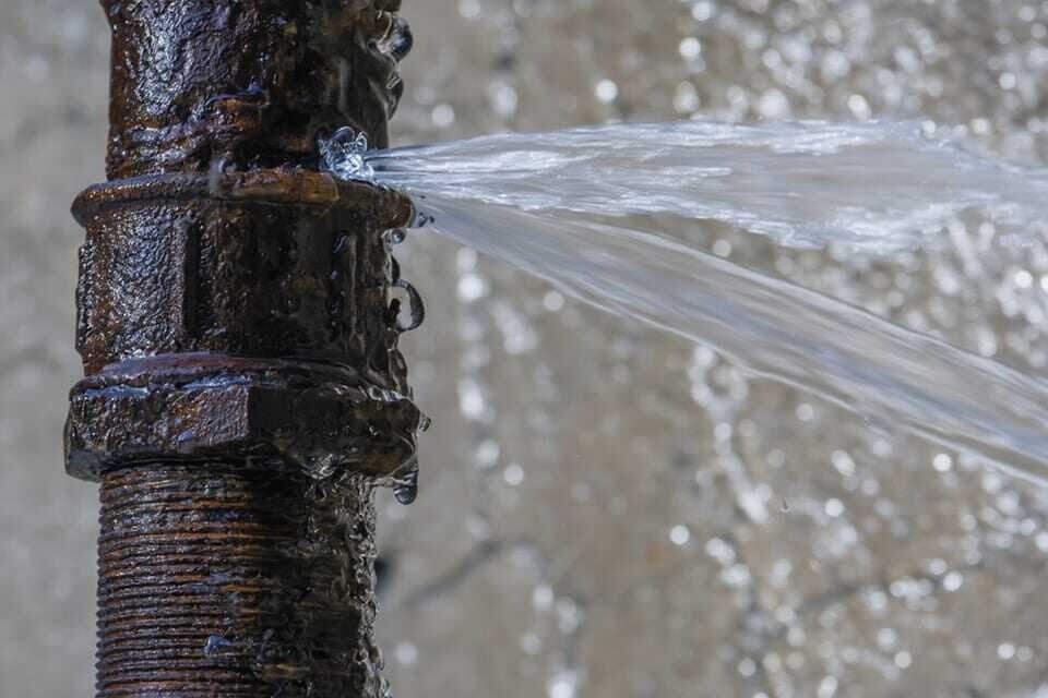 A burst water pipe spraying water after a Dallas, TX hard freeze
